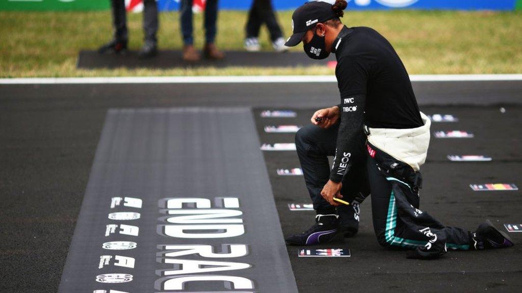 Lewis kneeling at the start of a race