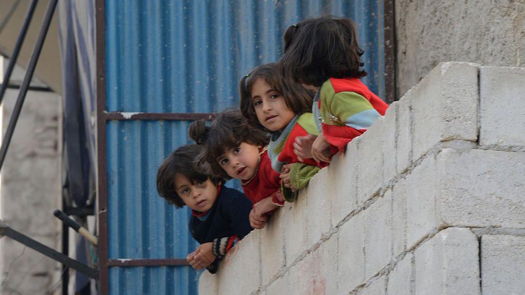 This picture from 2012 shows children watching an anti-government protest in Aleppo, in Syria.