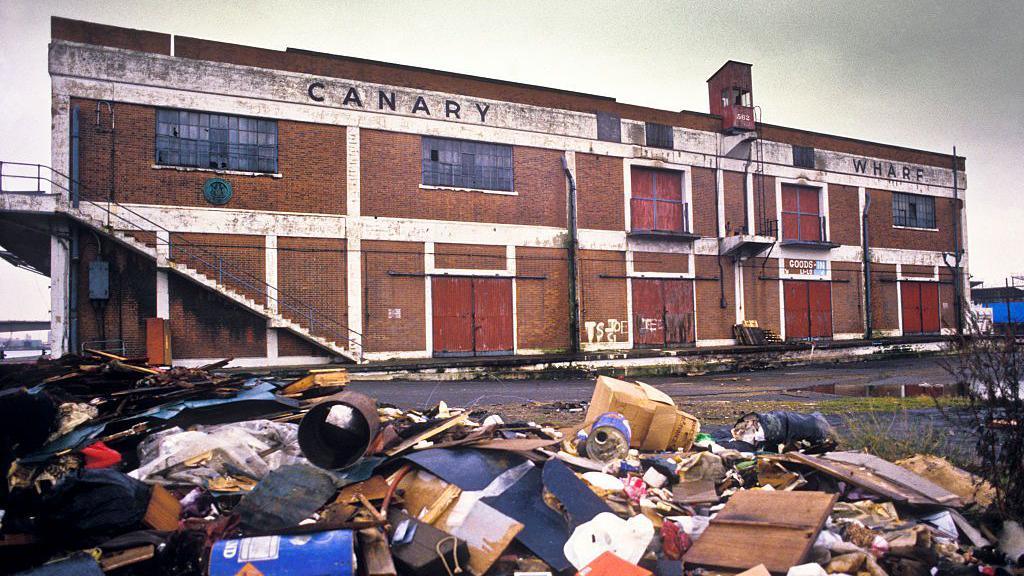 Canary Wharf before redevelopment, with rubbish in the foreground and disused buildings behind