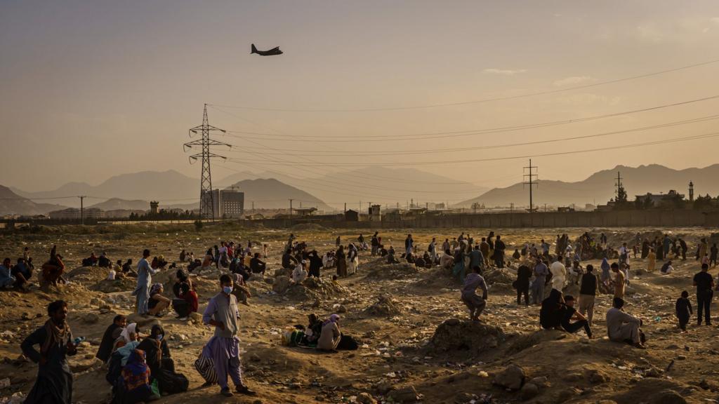 A military transport plane launches off while Afghans who cannot get into the airport to evacuate, watch and wonder while stranded outside, in Kabul, Afghanistan, Monday, Aug. 23, 2021.