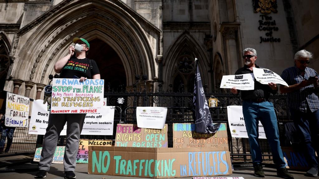 Protesters hold placards opposed to the government's Rwanda refugee scheme during a demonstration in the summer