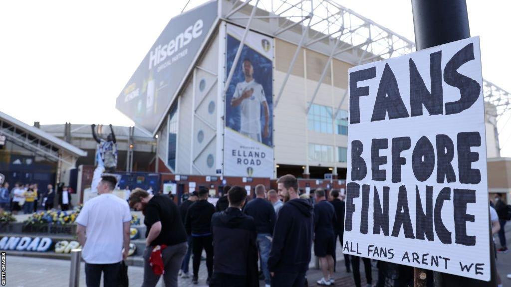 A sign saying "fans before finance" outside Elland Road stadium