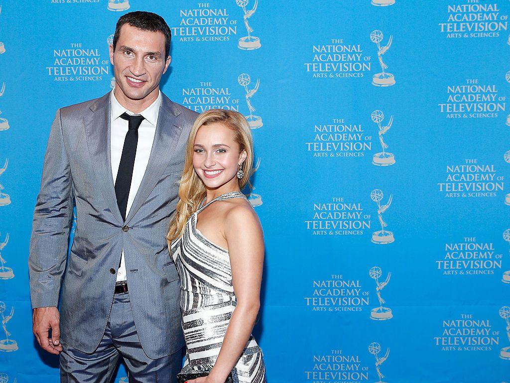 Wladimir Klitschko in a grey suit, white shirt and black tie is pictured smiling with his arm around Panettiere, who is smiling and has long blonde hair and wears a silver and white halterneck dress at an Emmy Awards reception in 2013. 