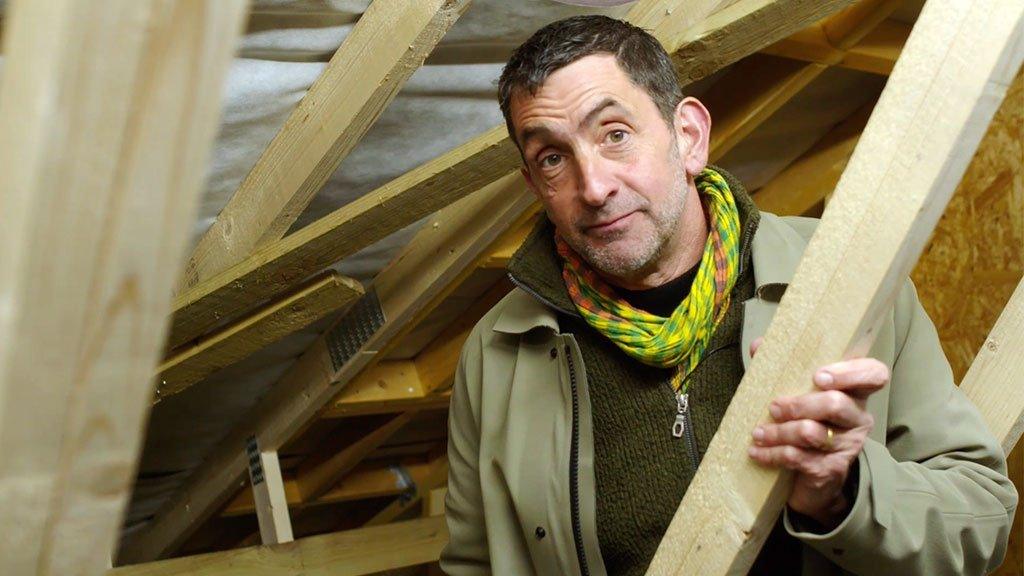 Justin Rowlatt stands in the loft of a house