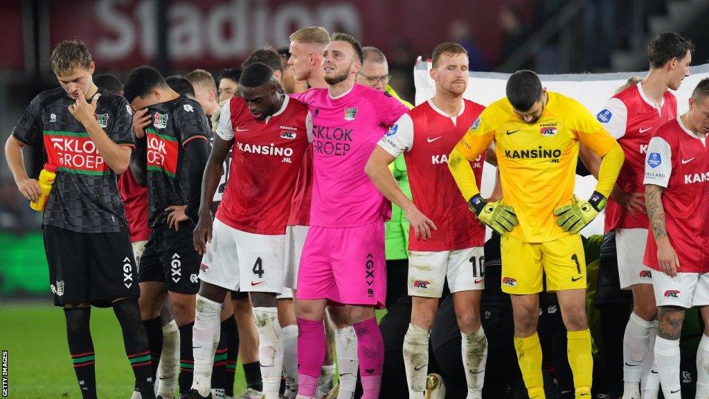 Players of NEC Nijmegen and AZ Alkmaar stand around Bas Dost after he collapses