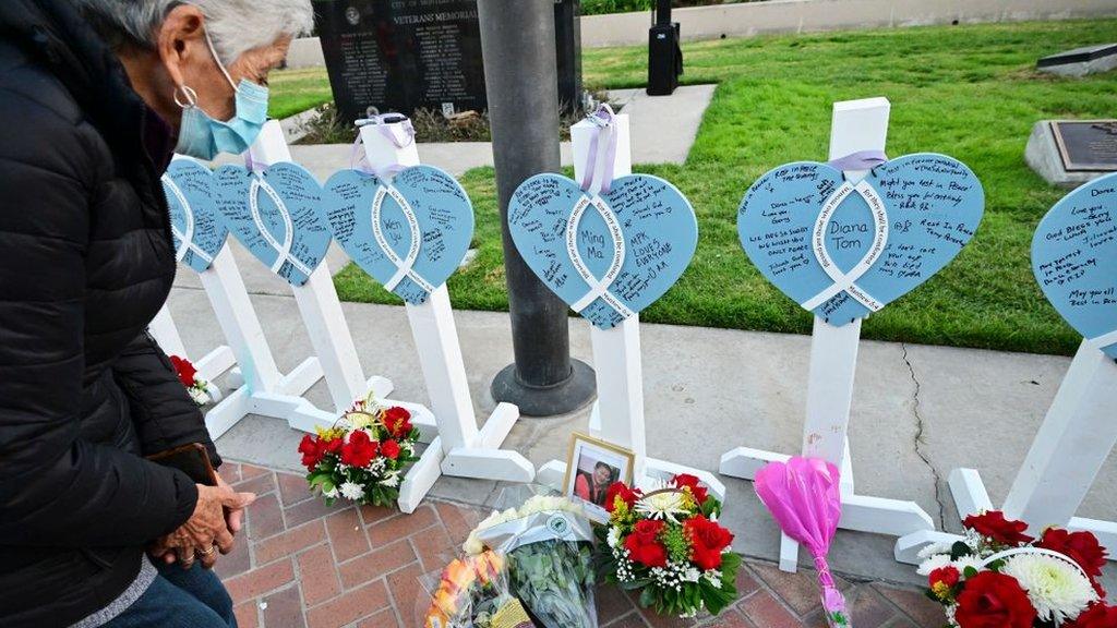 A mourner takes a closer look at a memorial for the 11 people killed in a shooting in Monterey Park on the eve of Lunar New Year