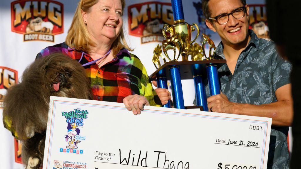 dog owner holding check and dog, next to man holding trophy