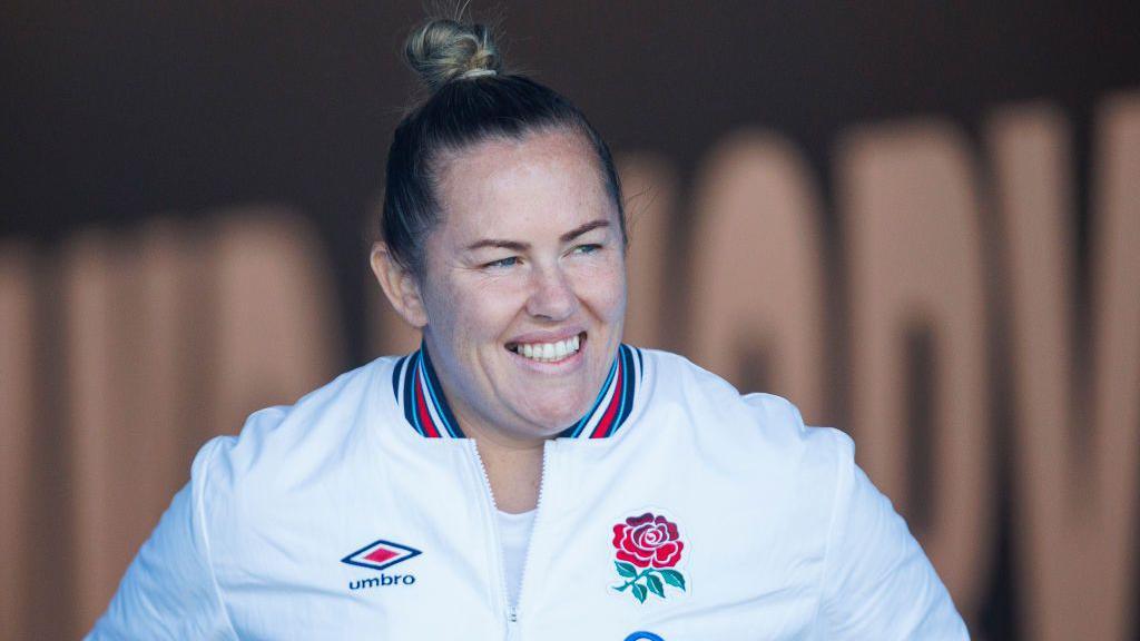 Marlie Packer wearing an England tracksuit smiles