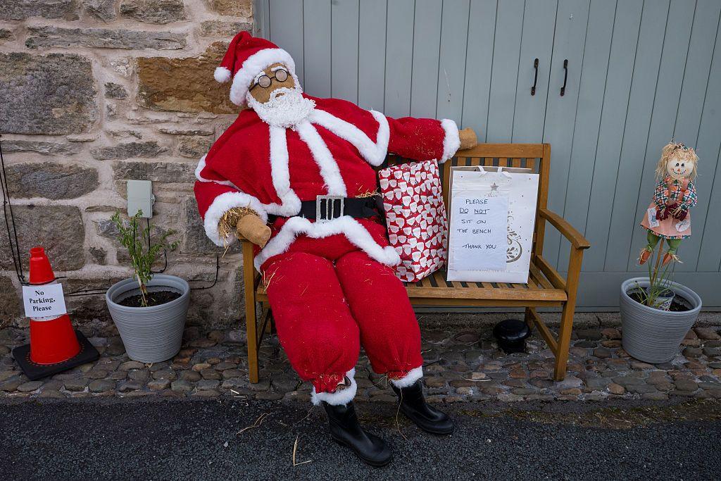 This display shows Father Christmas sitting on a bench with a wrapped present next to him