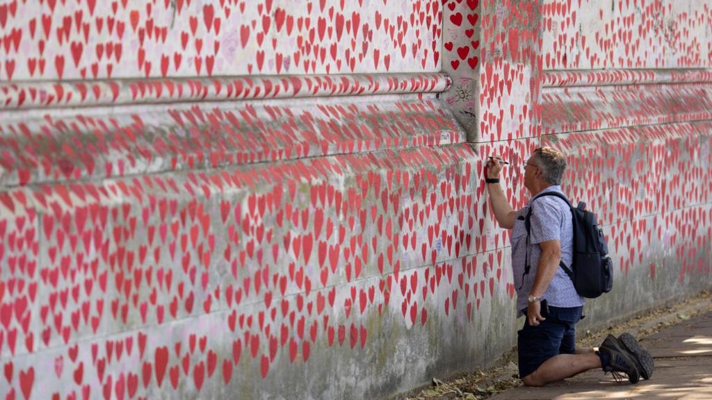 A man writes on the Covid memorial wall in London