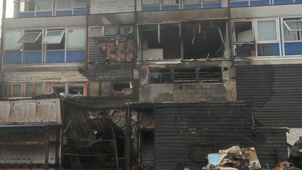 A community hub that has been burnt. Some of the windows hvae been taken out and there is a lot of rubble around the building.