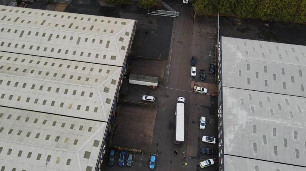 An aerial image of a depot with parked cars and lorries scattered around. 