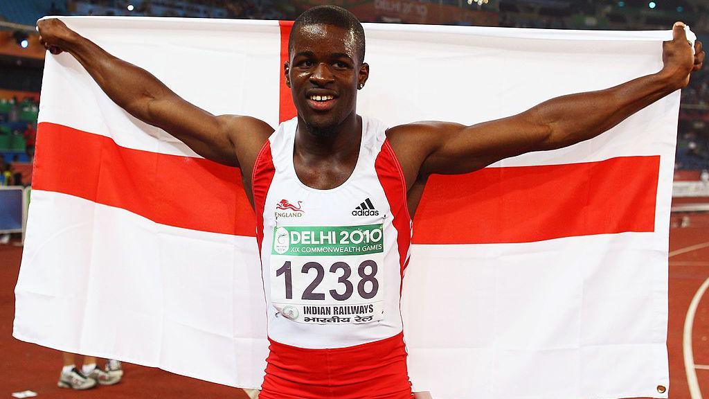 Sprinter Leon Baptiste celebrates by stretching an English flag behind him after winning the gold medal in the 200m at the 2010 Commonwealth Games in New Delhi, India