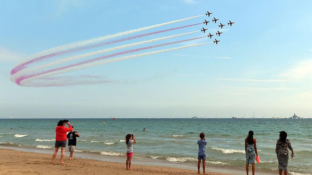 People look on from the beach as the Red Arrows aerobatics display team perform during the Bournemouth Air Festival.