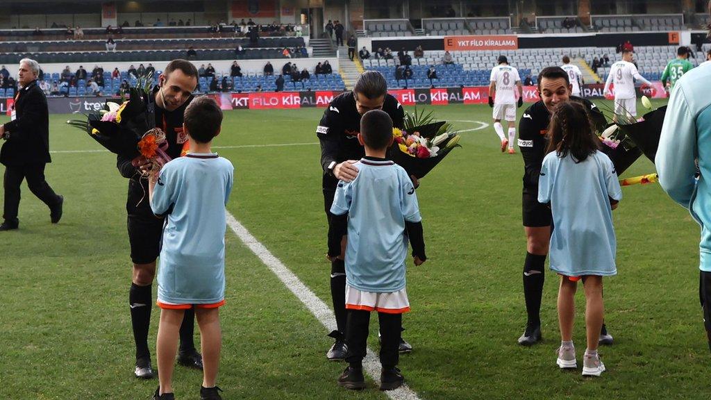 Children give flowers to the match officials before the Turkish Super League soccer match between Istanbul Basaksehir and Sivasspor