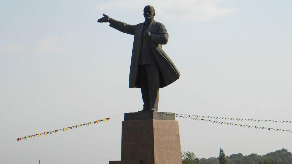 The statue of Vladimir Lenin, stood with an arm extended, against a grey sky in Osh Kyrgyzstan