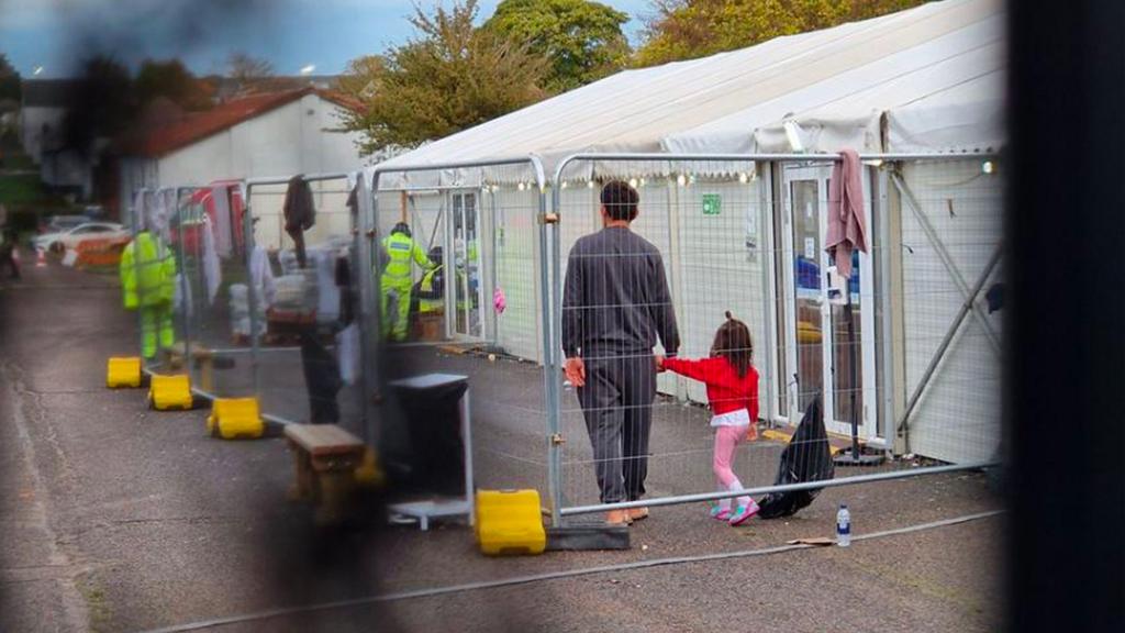 A small girl holding her father's hand at Manston centre in Kent