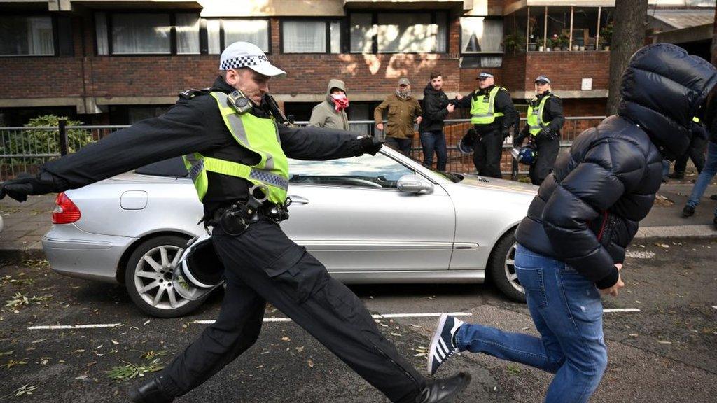 A police officer chases a man through streets close to the 'National March For Palestine' in central London on November 11, 2023, as counter-protest groups are monitored by police close to the route of the main march