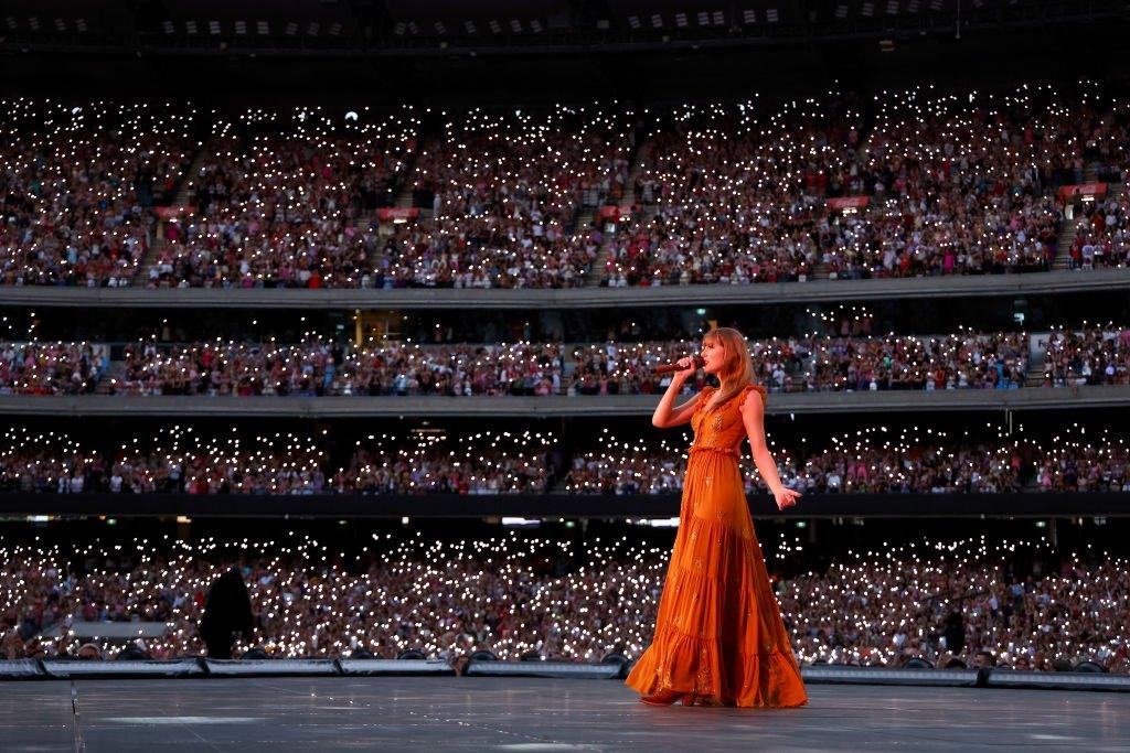 Taylor Swift performs in front of a large crowd.