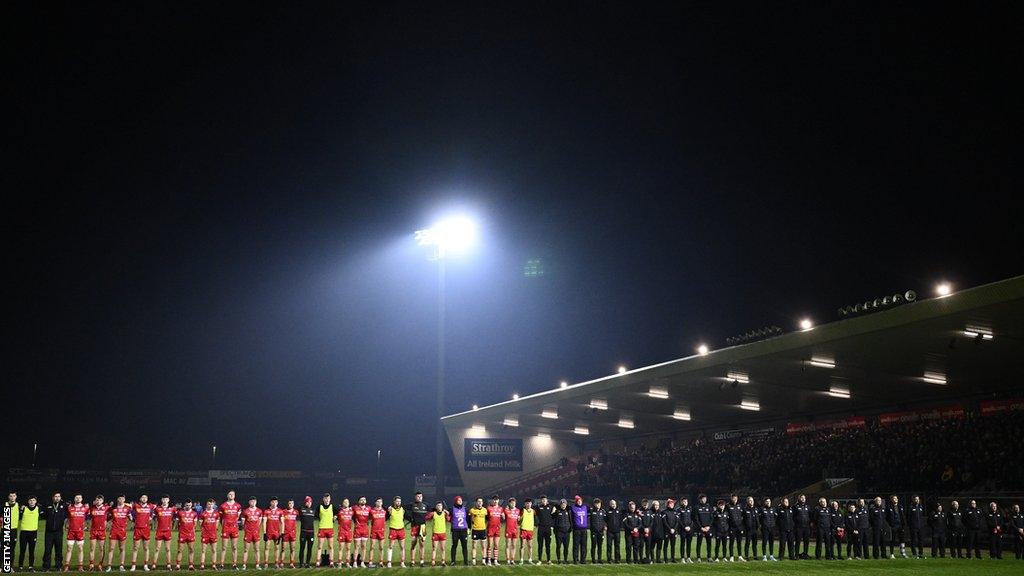 The Tyrone team and backroom staff stand for a minute's silence in memory of Caolan Devlin at Healy Park on Saturday evening