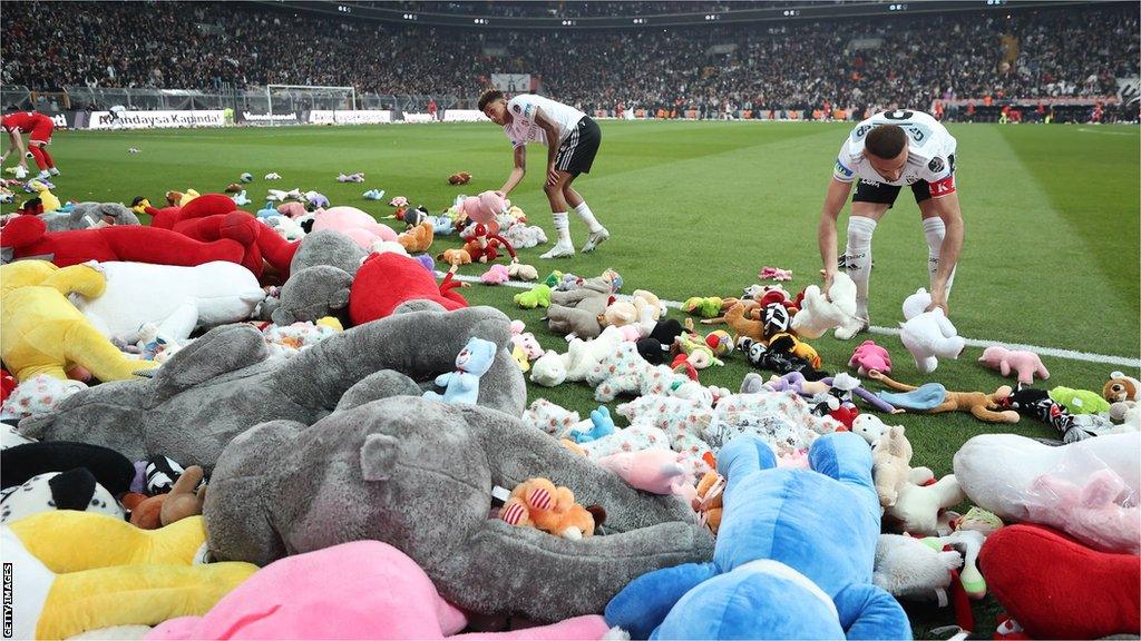 Players clear the pitch after Besiktas throw Teddy bears onto the field in support for the earthquake victim children