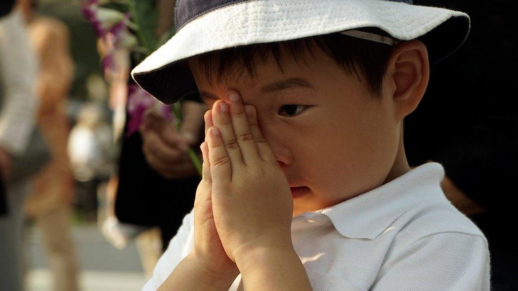 A boy prays for the atomic bomb victims in front of the cenotaph at the Hiroshima Peace Memorial Park in Hiroshima, western Japan, early Thursday, Aug. 6, 2015. Japan marked the 70th anniversary of the atomic bombing on Hiroshima.