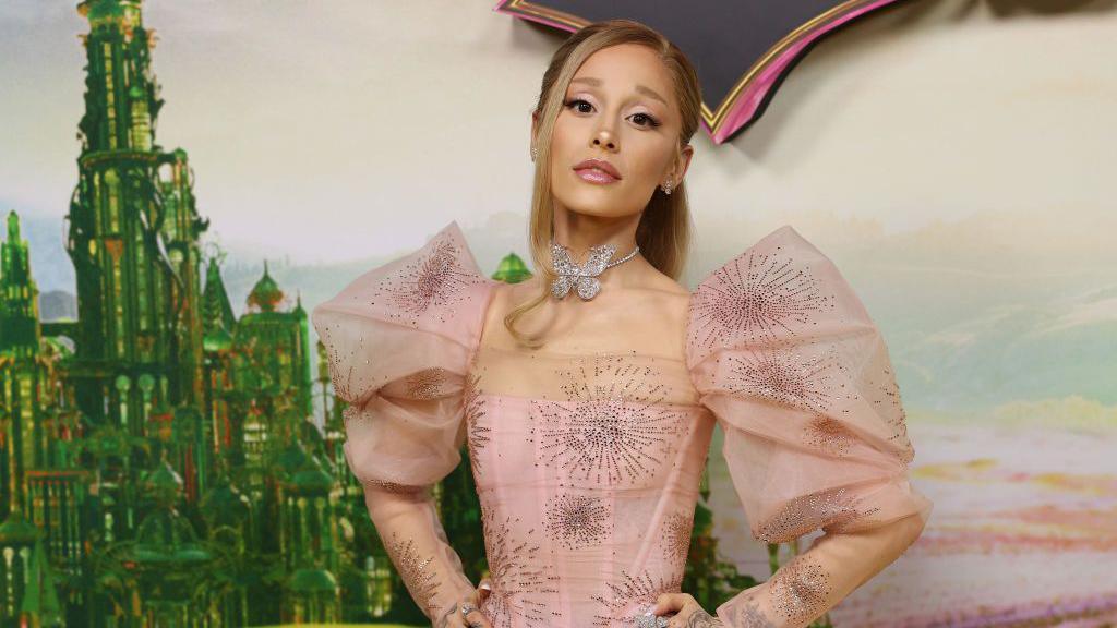 ariana grande poses at a wicked premiere in a glinda inspired dress with a butterfly choker