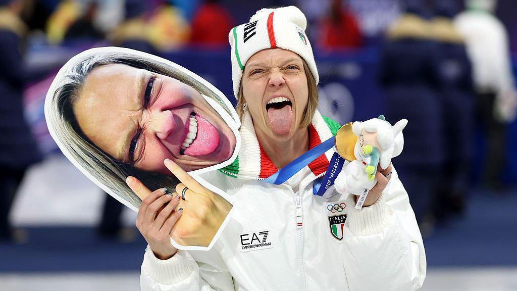 Arianna Fontana of Team Italy poses for a photo with her gold medal and a face mask of herself after the medal ceremony for the Short Track Speed Skating Mixed Team Relay on day four
