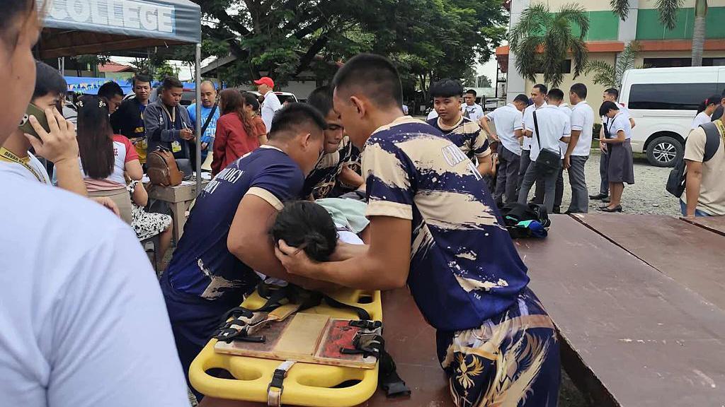 Rescuers helping a student onto a stretcher outside the Davao De Oro State College in Davao