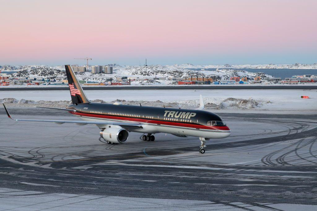 Donald Trump Jr's plane, emblazoned with 'Trump' across the front, at Greenland's Nuuk airport. Ice can be seen on the runway and a snowy landscape behind.