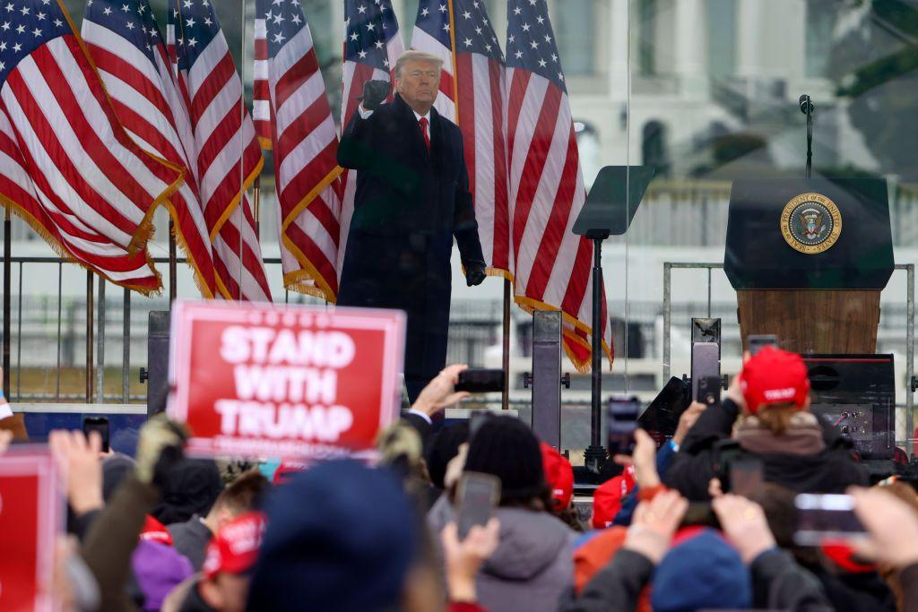 Donald Trump raises a gloved fist to greet the crowd at a rally on January 06, 2021, in Washington, DC. One member of the crowd is holding a Stand with Trump placard.