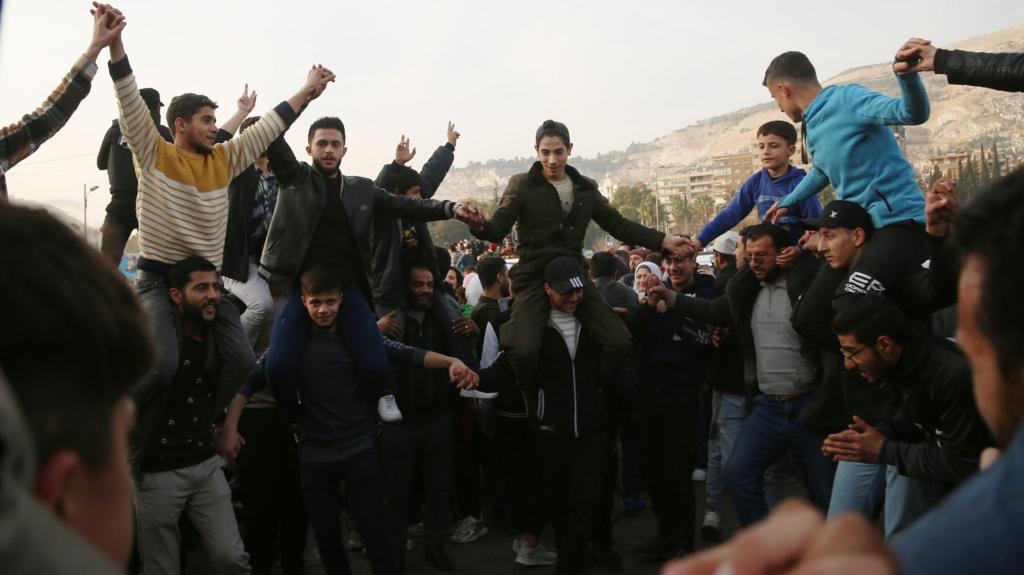 People celebrate the overthrow of Syrian President al-Assad,