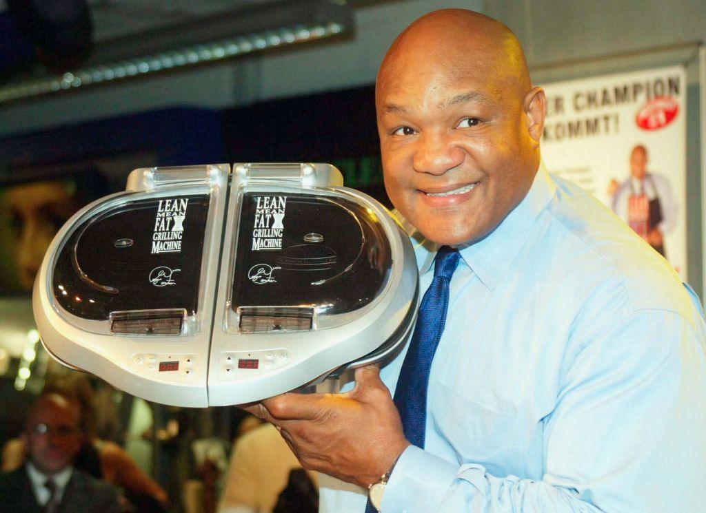 Foreman holding one of his grills and smiling