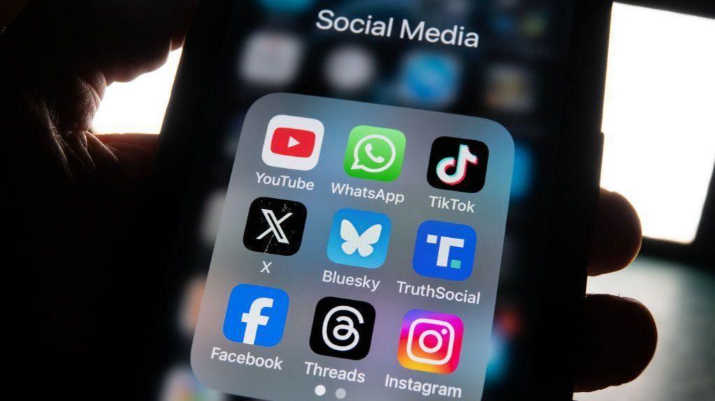 Close up of a mobile phone screen showing icons for nine social media apps, including Facebook, Instagram and X.