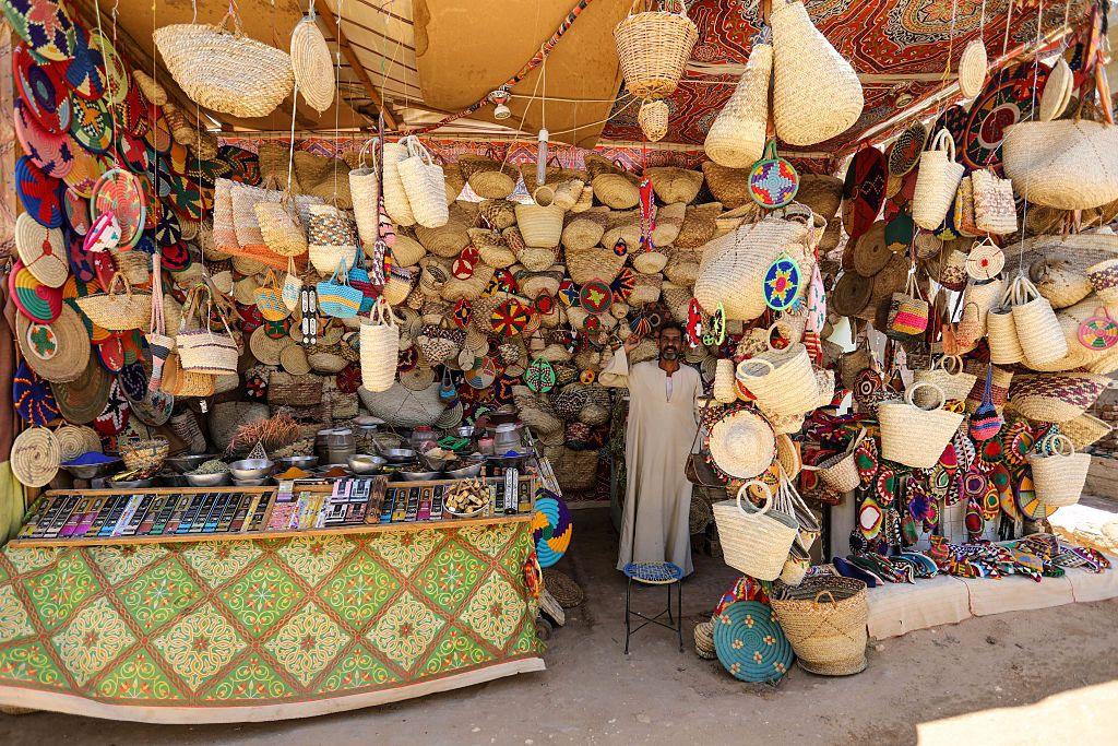 Man stands in the middle of an exhibition stall stocking several bags...