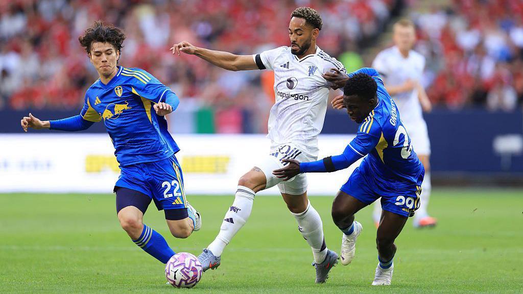 Manchester United playmaker Matheus Cunha dribbles between Leeds duo Ao Tanaka and Willy Gnonto