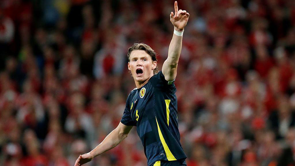 Scott McTominay with his hand in the air while playing for Scotland