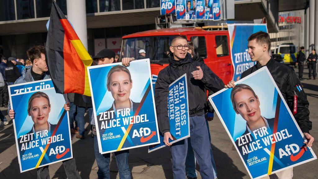 Pro-AfD supporters hold up placards of Alice Weidel with the message "Time for Alice Weidel"