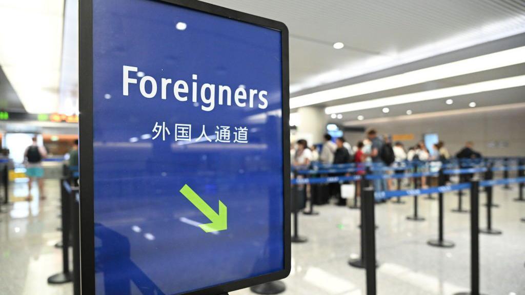 A sign at a Chinese immigration checkpoint says "foreigners", with an arrow pointing to a lane for foreign visitors