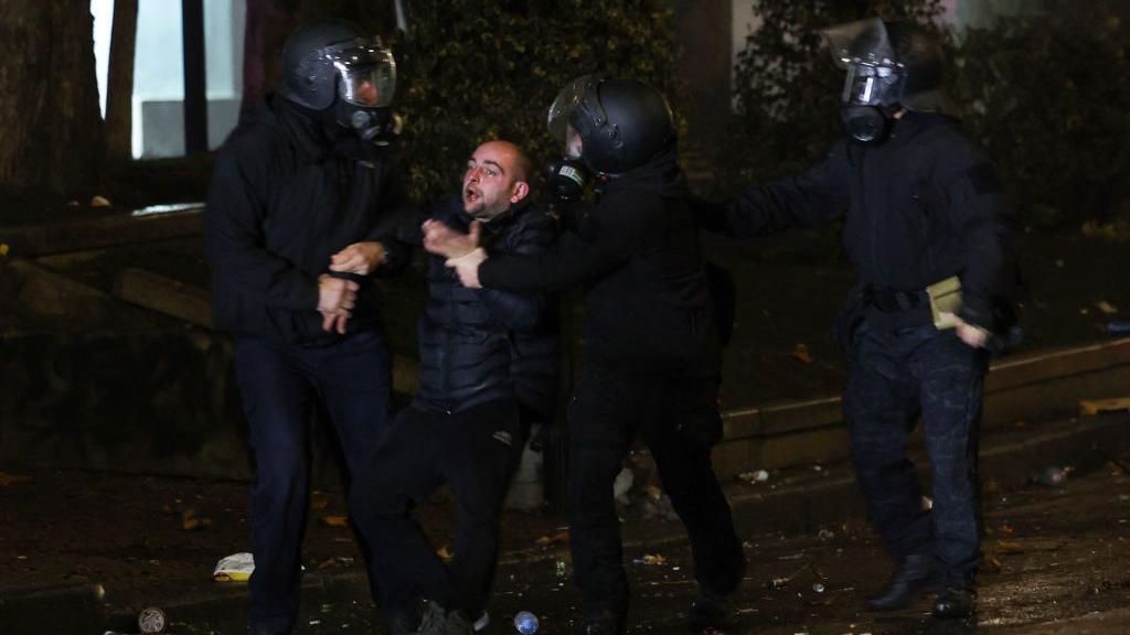 A demonstrator is detained by police during protests in Tbilisi