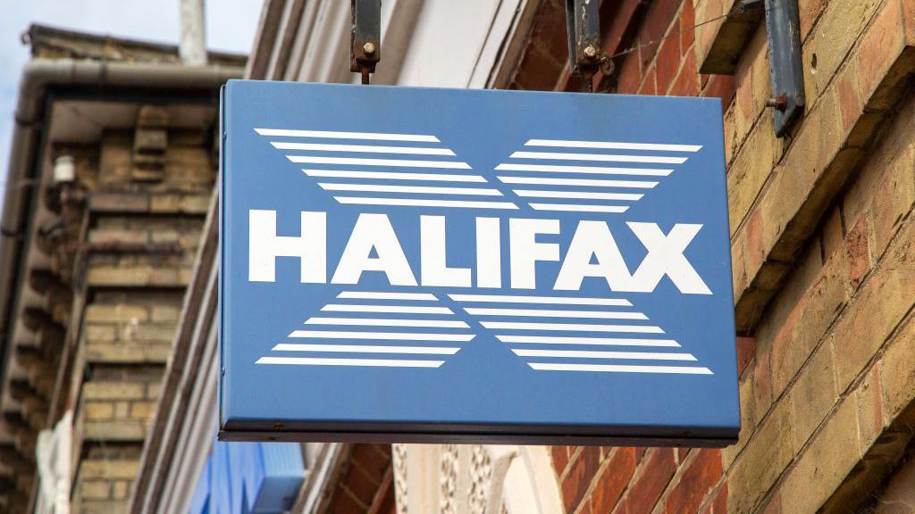 Close-up image of a Halifax sign in blue and white, hanging off a traditional high street building.