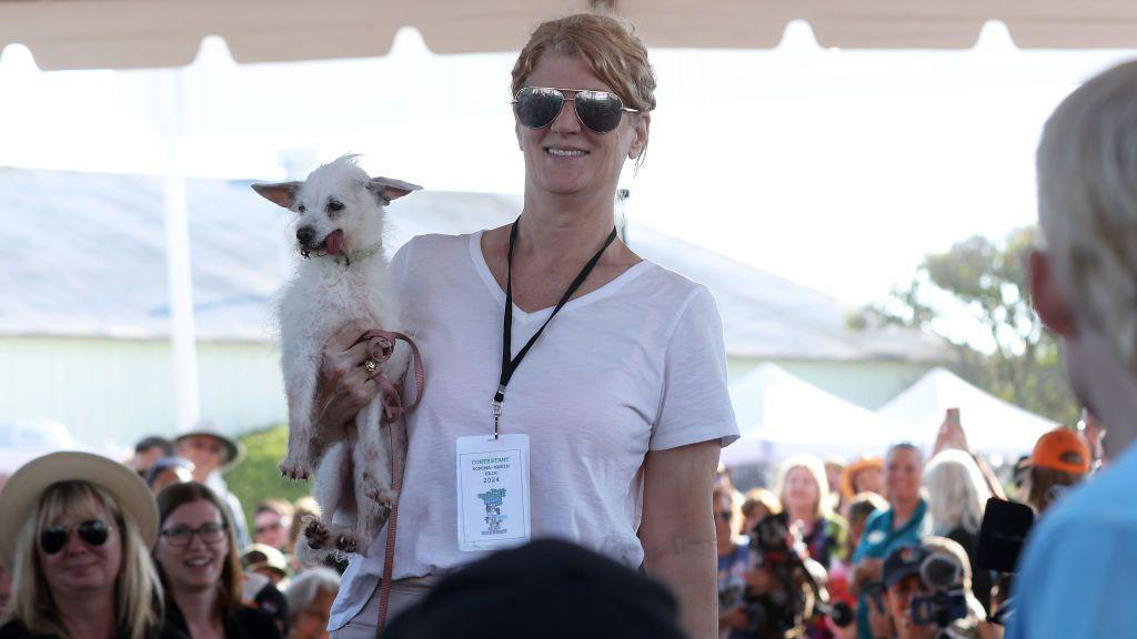 white dog being carried by owner