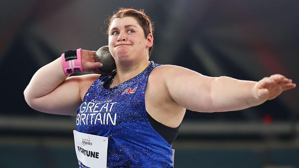 Sabrina Fortune in action, holding the shot near her neck and getting ready to throw.