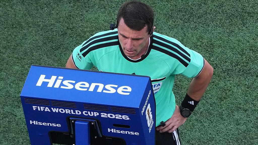 A referee looks into a blue VAR monitor