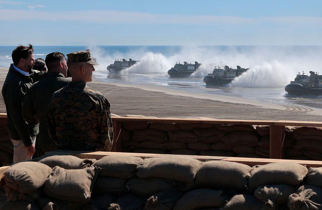 JD Vance watches along side military members as boats reach the shores of a beach