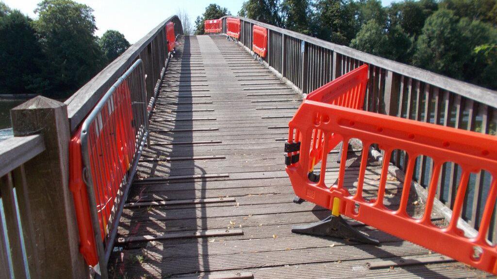 Red plastic blockades can be seen blocking part of a wooden footbridge.