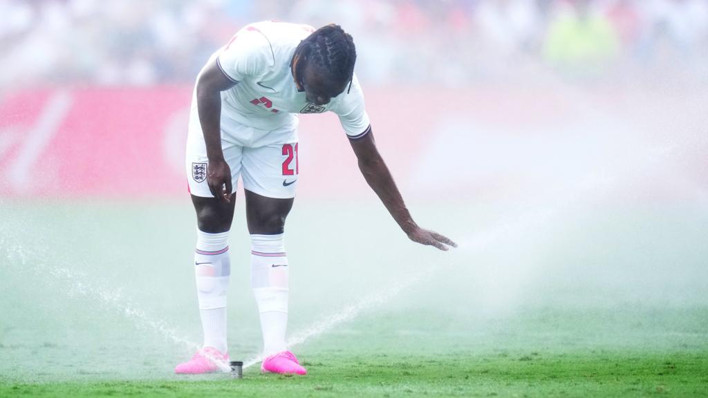 Eberechi Eze puts his hand in the water being sprayed onto the pitch