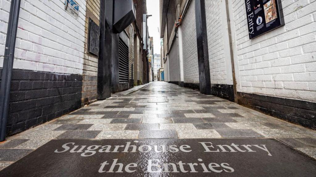 An alley way with a sign that says Sugarhouse Entry 