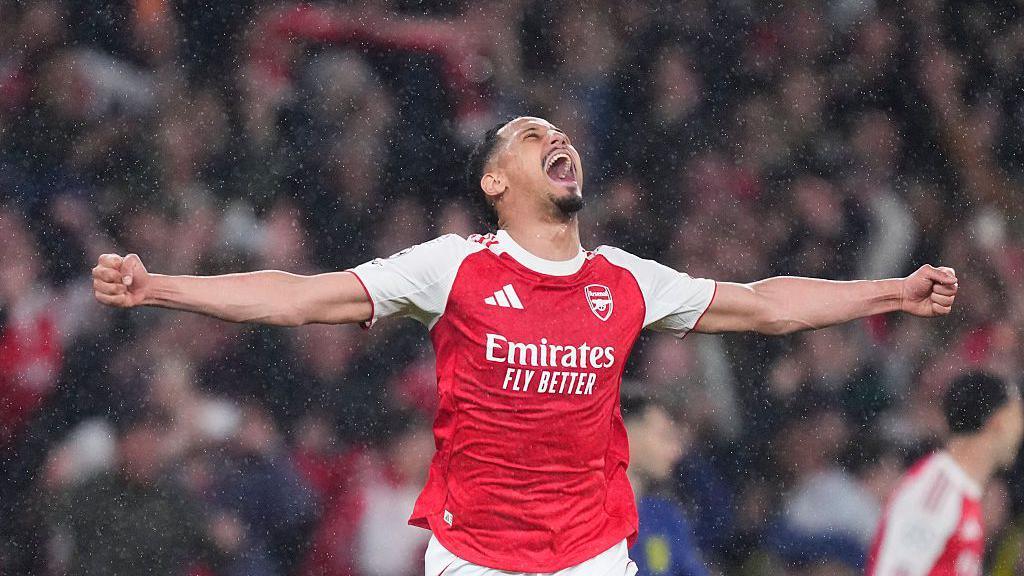 William Saliba centre-back of Arsenal and France celebrates the victory in the rain with his arms stretched wide after winning the UEFA Champions League semi-final