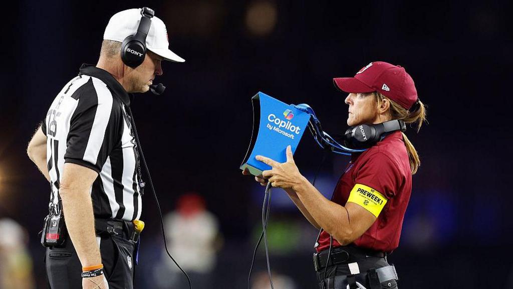 An official views the instant replay monitor during the NFL preseason game between Washington Commanders and New England Patriots